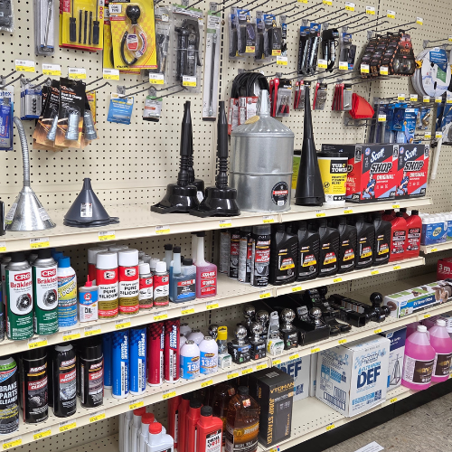 Store shelf displaying automotive supplies like oil, cleaning products, funnels, and wiper blades. Organized by type on pegboards and shelves.