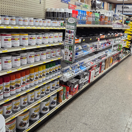 A store aisle with shelves displaying a variety of spray paints, sealants, and DIY tools. The area is well-organized, conveying a sense of order.