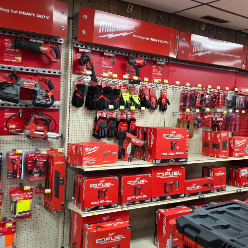 A store display showcases an array of Milwaukee tools and accessories. Red and black packaging dominates, highlighting power tools and gloves on shelves.