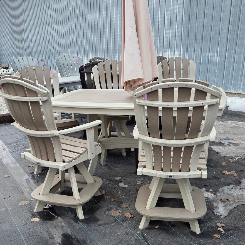 Outdoor patio set with six beige and brown Adirondack chairs around a rectangular wooden table. The scene includes a closed beige umbrella and scattered fall leaves.