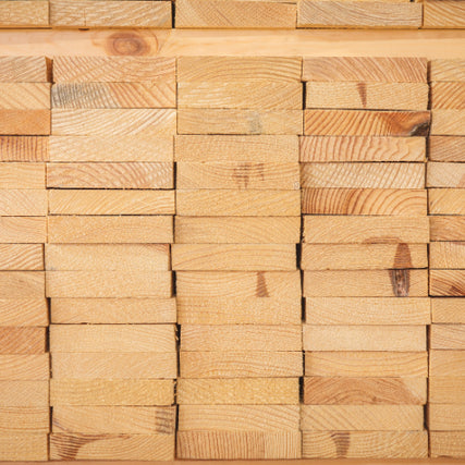 LumberStacked wooden planks with visible grain and texture, neatly arranged in rows. The uniform, light brown tones create a sense of order and warmth.